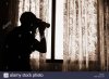 man-with-binoculars-looking-out-of-window-from-behind-net-curtains-C5N3DJ.jpg