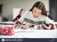 teenage-girl-writing-in-exercise-book-in-class-PAP6RA.jpg