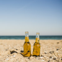 transparent-beer-bottles-sand-beach-against-clear-sky_23-2148103050.jpg